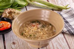 A bowl of soup on a table next to a bowl of vegetables photo