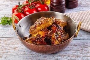 A bowl of chicken wings with tomatoes and herbs photo
