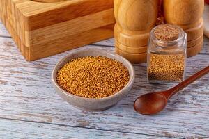 A wooden table with a bowl of mustard and spices photo