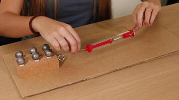 A person uses a spring scale to measure frictional force on a weighted block sliding over cardboard video