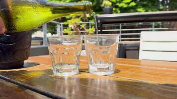 Water is poured into glasses on a sunlit outdoor table, creating a refreshing and vibrant atmosphere video