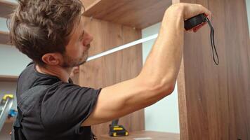 Man measuring wooden wardrobe with tape measure, Furniture assembling process video