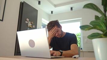 Man working on laptop at home and using remote control to adjust temperature on air conditioner video