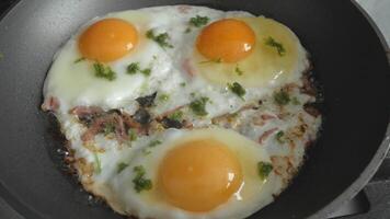 Fried fried eggs of three eggs fried with bacon in a frying pan. Breakfast preparation. view from above. video