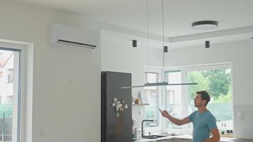Man Operating Air Conditioner With Remote Control in Modern Kitchen Interior video
