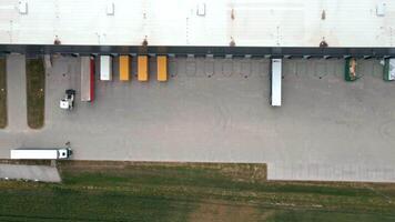 Aerial view of warehouse loading platforms with parked trailers and cargo trucks in operation video