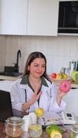 Close-up of a nutritionist looking at the camera at a table with fruits and vegetables. Consultation on proper nutrition using a donut as an example of unhealthy food. video