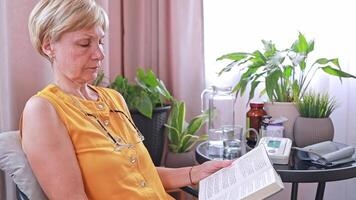 An elderly woman wearing glasses reads a book in her apartment and has difficulty perceiving the text due to farsightedness and age-related vision changes. Farsightedness, cataract, glaucoma, optics. video