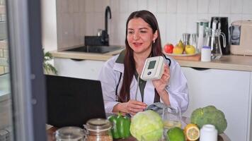 A nutritionist works with patients online at a table, showing a tonometer and capsules of pills. Consultation for people with high blood pressure. Health and diet concept, clinic, wellness. video