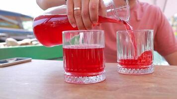 A man pours cool berry juice into a glass outside in summer. Refreshing drinks help quench thirst and restore strength. Cafe concept, restaurant, gastronomy. video