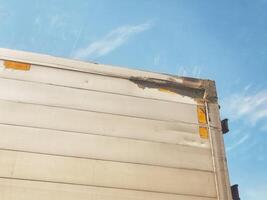 Examining Damaged Truck Trailer Corner Against a Blue Sky Backdrop photo