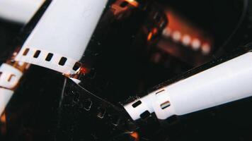 A detailed view of a film roll with visible perforations and a polished surface. Against a dark background photo