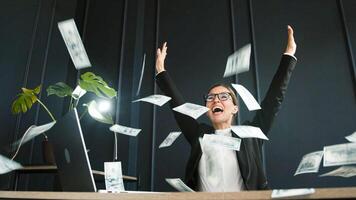 A successful middle-aged businesswoman enjoys a stack of money from a successful deal and closed contract in her office. Perfect for themes of business success. photo