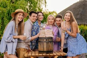 Happy friends drinking beer and enjoying each other company at a BBQ dinner in nature, with sausages on the table waiting to be grilled. Concept food and friendship, promoting BBQ photo