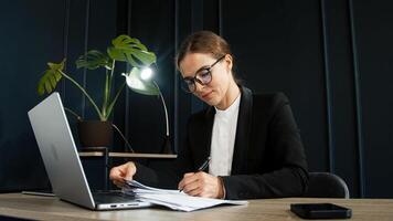 A stylish young woman working on a laptop in a modern office setting. Ideal for concepts of productivity, business, and a contemporary work environment. photo