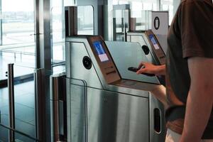 Close up of young man uses his smartphone to scan a boarding pass at an automated airport gate. Concept of digitalization, self-check-in and independent travel. photo