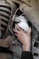 Mechanic's hand reaches out to install or remove an oil filter on the underbody of a car. Changing an oil filter. photo