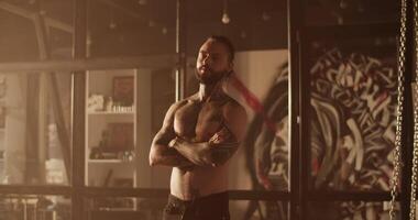 Self assured fit tattooed man standing in salon with folded arms video