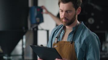 Male worker Caucasian man expert technician inspect coffee roasting factory check roaster machine writing checklist quality control caffeine manufacture write notes business owner production industry video