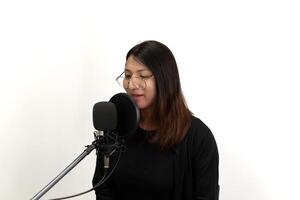 A woman singing into a microphone in front of a white background photo