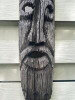 A wooden face mask with a beard on a wall photo