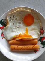 A plate with an egg, hot dog, and a fried egg photo