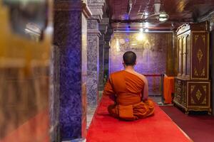 A monk sitting in a temple with a red carpet photo