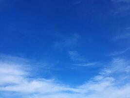 A blue sky with clouds and a few people flying kites photo