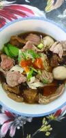 A bowl of meat and vegetables with a flower pattern photo