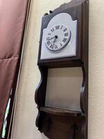 A clock mounted on a wall with a shelf photo