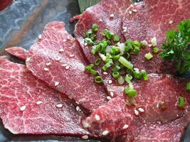 Sliced beef on a black plate with sesame seeds photo