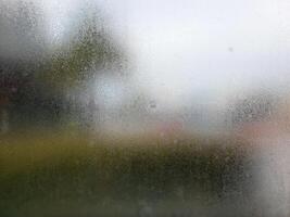 A blurry view of a wet window with a street in the background photo