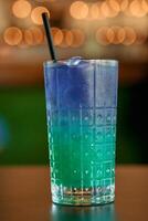 Refreshing blue and green gradient iced drink in a textured glass with straw photo