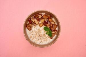 Delicious cinnamon apple oatmeal with mint on pink background photo