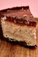 Delicious chocolate peanut butter cheesecake slice with rich ganache on wooden board photo