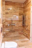 Modern walk-in shower with glass enclosure and brown tile design photo