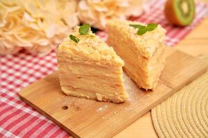 Delicious napolean cake slices on wooden board with floral and kiwi accents photo
