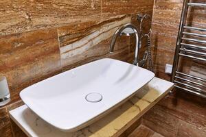 Modern bathroom with white sink and chrome faucet on marble countertop photo