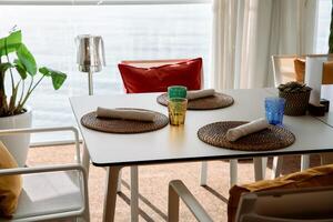 Seaside dining setup with woven placemats and colorful glasses on table photo