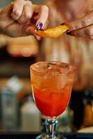 Refreshing cocktail garnished with orange peel twist by bartender for summer enjoyment photo