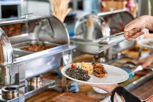 Buffet serving of grilled chicken and lentils with tongs at catering event photo