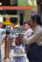 A man is standing behind a bar with a beer photo