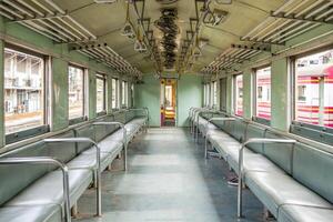 A train car with empty seats and a metal railing photo