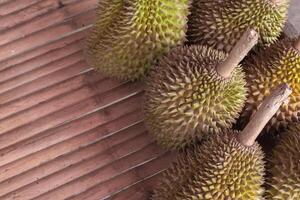 A bunch of durian fruit sitting on a wooden table photo