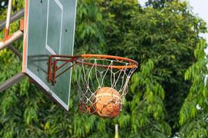 A basketball is hanging from the rim of a basketball hoop photo
