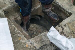 A man standing in a hole with a bag of trash photo
