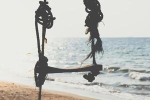A swing hanging from a rope on the beach photo