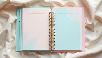 Open Pastel Notebook with Gold Spiral Rings on Cream Satin Fabric photo