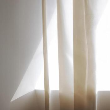 A white curtain is hanging in front of a window photo