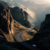 A winding road in the mountains with a mountain range in the background photo